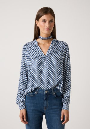 Blue patterned blouse with a collar and long sleeves, featuring a matching neck scarf. The design includes alternating blue and white shapes.