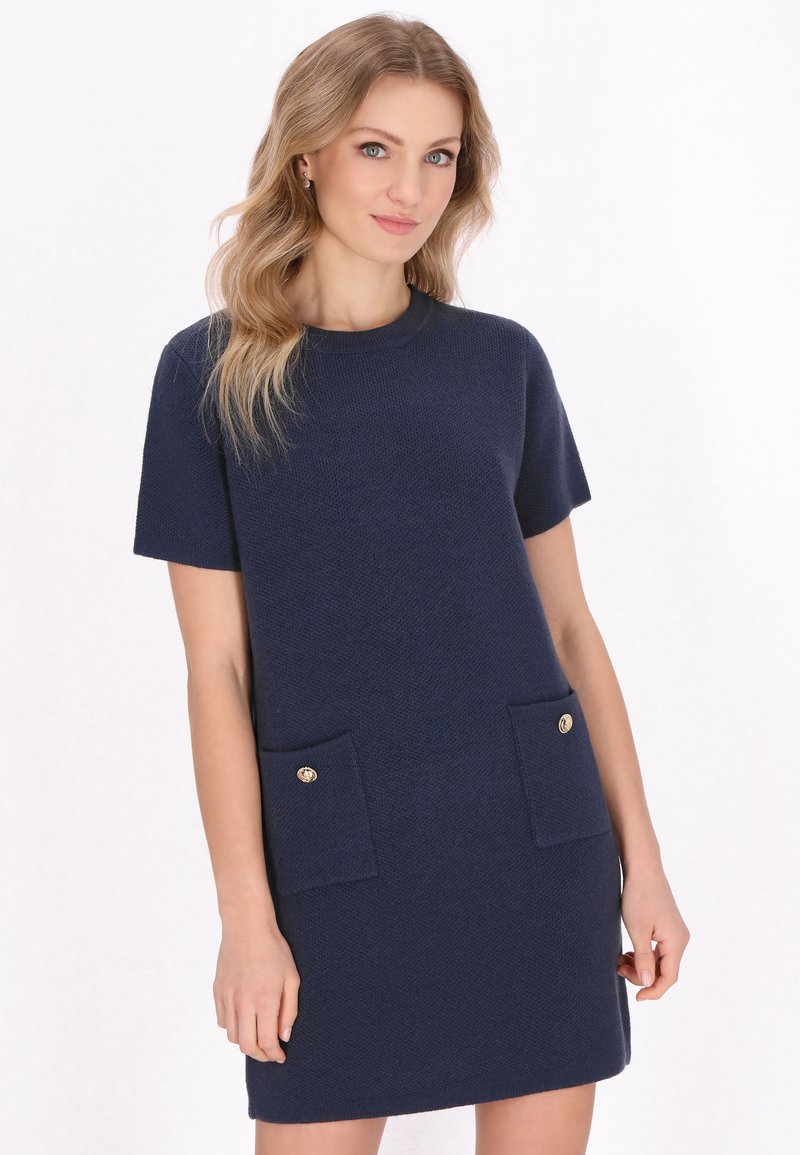 Abito blu navy a maniche corte con un tessuto strutturato, dotato di due tasche frontali con bottoni dorati per un tocco di dettaglio.