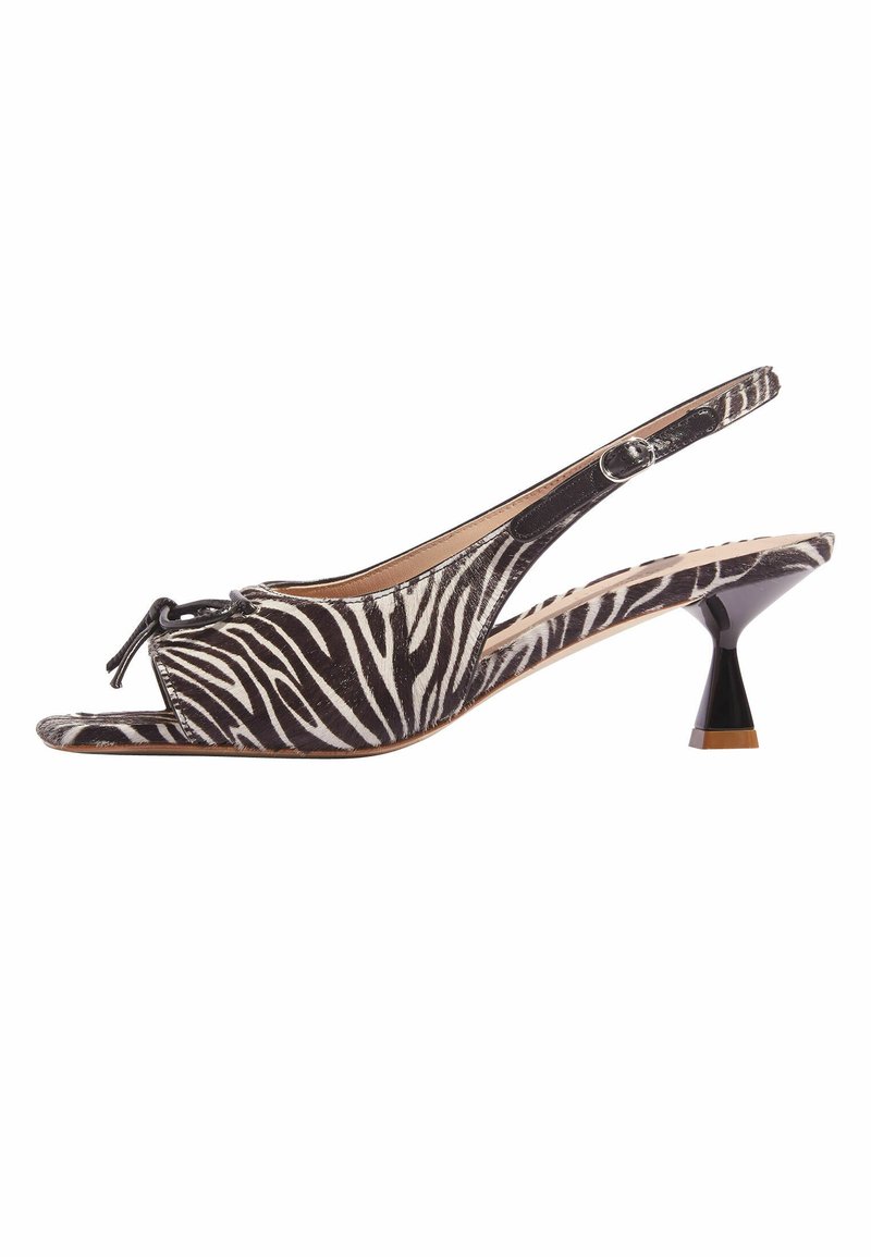 Scarpa slingback in stampa zebra bianco e nero con punta aperta, dettaglio a fiocco nella parte anteriore e tacco affusolato con un accento a contrasto.