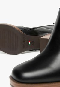 Schwarze Lederstiefelette mit Holzabsatz, ausgestattet mit einem Reißverschluss und einer Branding auf der Sohle. Größe 37, gefertigt in Italien.