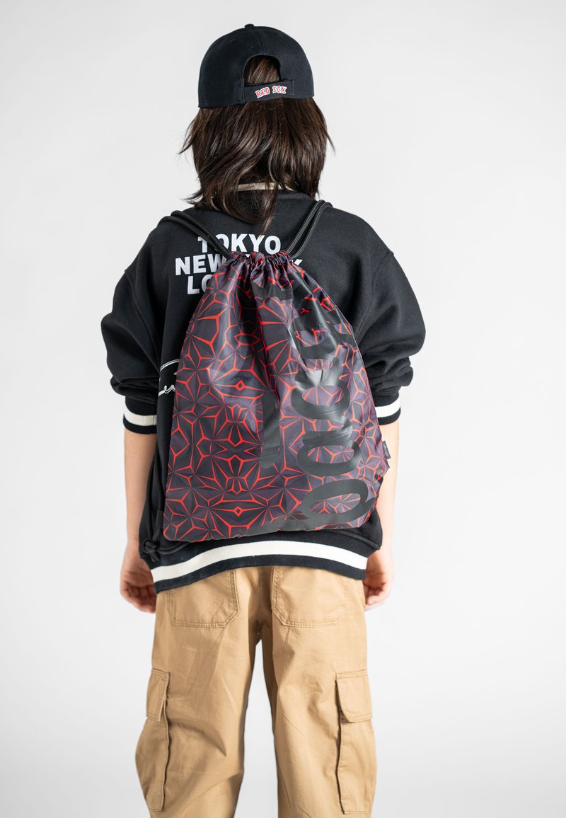 Taška na stažení v černé barvě s červeným geometrickým vzorem. Má odolnou texturu a kontrastní bílé detaily na spodní části.