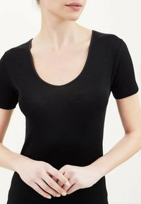 Top nero a maniche corte con scollatura a girocollo. Realizzato in tessuto liscio, presenta un design aderente e dettagli di cucitura sottili lungo i bordi.