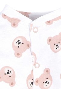 Weißer Stoff-Overall mit einem wiederholten Muster von hellbraunen Teddybär-Gesichtern und Druckknöpfen auf der Vorderseite für den Verschluss.