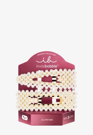 Dos horquillas rectangulares doradas decoradas con perlas sobre una tarjeta granate con la marca invisibobble Clipstar.