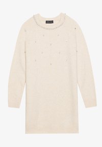 Pull en maille beige à manches longues, col rond orné de gemmes et de décorations dispersées sur le devant.