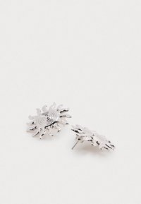 Strieborné náušnice v tvare slnka so spirálovými vzormi, s textúrovanými lúčmi a zátkou na zadnej strane, vyrobené z kovového materiálu.