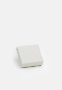 Kvadratisk hvid sæbe med en glat overflade. Har et subtilt prægget logo på den øverste flade. Kompakt og minimalistisk design.