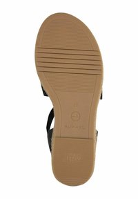 Black sandal with a textured strap, featuring a tan rubber sole with grip lines. Brand logo and size embossed on the sole.