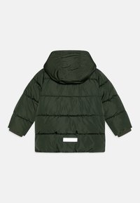 Mörkgrön puffjacka med huva, med kviltade sektioner, elastiska ärmslut och en reflekterande detalj på baksidan. Mjuk, texturerad tyg.