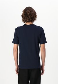 Camiseta de manga corta azul marino con cuello redondo, fabricada en tejido suave, que presenta una textura lisa y un diseño sencillo, vista desde la parte de atrás.