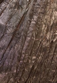 Textured fabric in metallic bronze, featuring a wavy pattern with varying shades, creating depth with a reflective sheen and subtle creases.