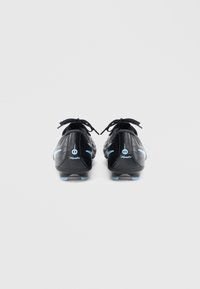 Μαύρα ποδοσφαιρικά παπούτσια με κομψό σχεδιασμό, που διαθέτουν ανοιχτό μπλε λεπτομέρειες και υφή στο πάνω μέρος, με μαύρα κορδόνια και διαμορφωμένες τάπες.