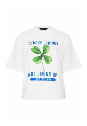 Camiseta blanca de manga corta con un trébol de cuatro hojas verde y texto azul: "Las cosas afortunadas se están alineando, confía en el momento."