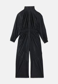 Juodas ilgomis rankovėmis kombinezonas su aukštu kaklu, surinkta liemens dalimi ir rankogaliais, priekyje užtrauktukas ir plataus sijono kelnės, išdėliotas ant balto fono.