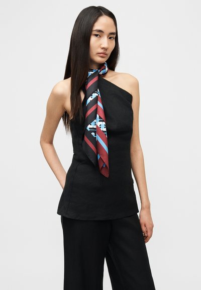 Μαύρο τοπ ενός ώμου με υφασμάτινη υφή, σε συνδυασμό με πολύχρωμο μεταξωτό μαντήλι με έντονα μοτίβα και αντιθετικές ρίγες.