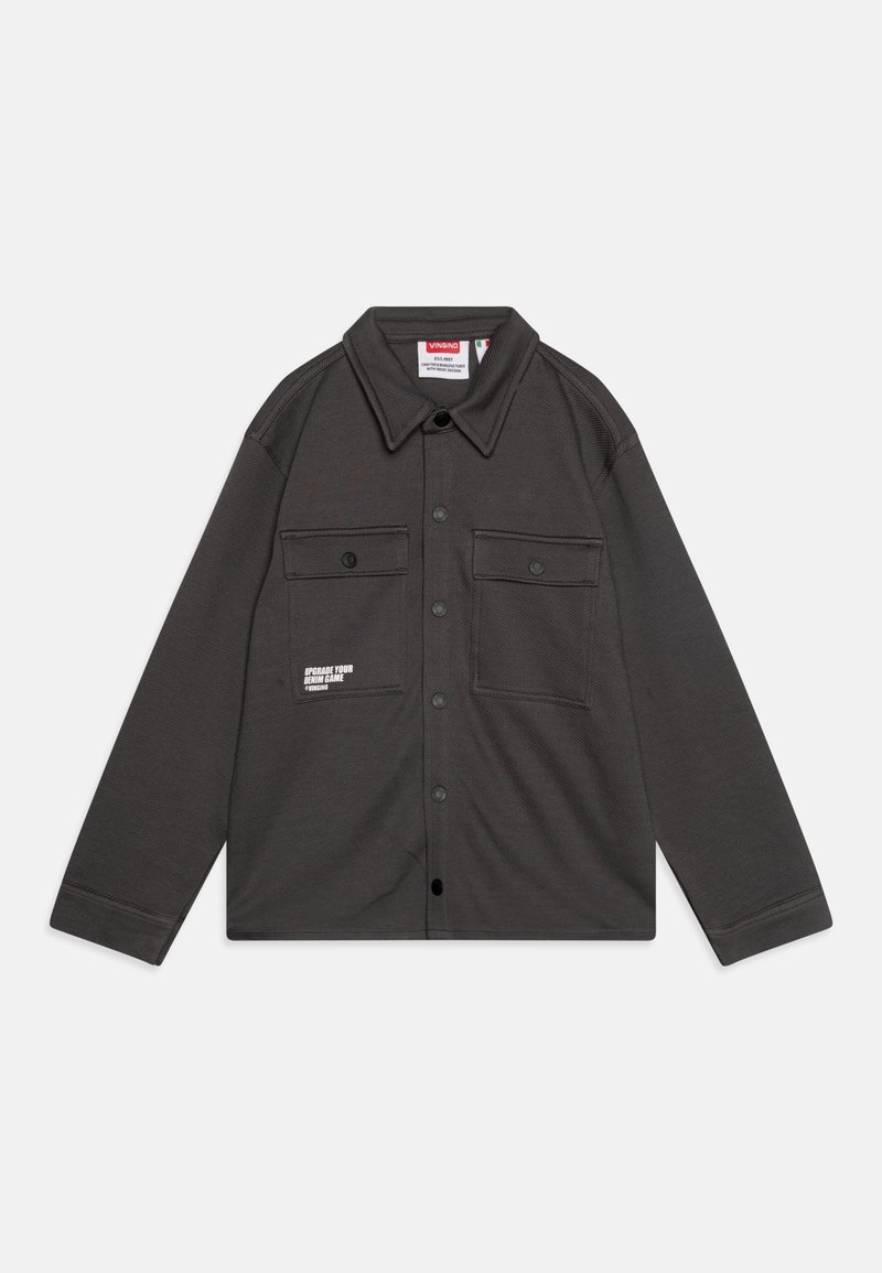 Camisa negra de algodón con cuello, dos bolsillos en el pecho, un acabado texturizado y texto impreso en blanco en la zona del bolsillo izquierdo.