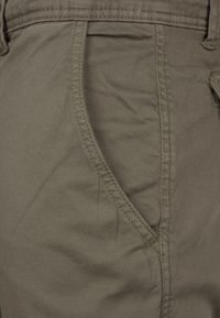 Pantalones de algodón color caqui con un bolsillo frontal, textura suave y costuras limpias a lo largo de las costuras.