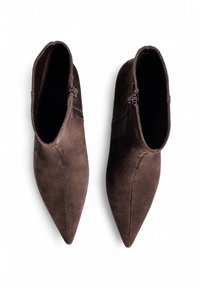 Botines de ante marrón con punta afilada y cierre de cremallera. Textura suave y diseño minimalista. Costura clara que acentúa la forma.