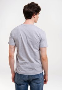 Graues Baumwoll-T-Shirt mit kurzen Ärmeln, Rundhalsausschnitt und glatter Textur, kombiniert mit blauen Jeans. Die Rückansicht betont das schlichte Design.