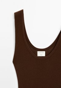 Canottiera marrone a coste con scollatura ampia e spalline spesse. Presenta un'etichetta con "Massimo Dutti Studio" cucita all'interno. Tessuto dalla consistenza liscia.