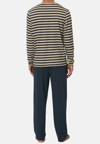Chemise à manches longues rayée beige et marine, associée à un pantalon ample marine foncé. Tissu doux avec un design décontracté et un style simple.