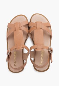 Sandali in pelle marrone con cinturini incrociati, fibbia regolabile alla caviglia e solette beige morbide. La suola in gomma piatta offre stabilità.