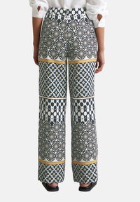 Pantalons à jambes larges avec un mélange de motifs géométriques en marine, blanc et or, en tissu texturé et avec une taille élastique.
