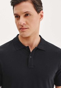 Czarna koszulka polo z kołnierzykiem na guziki i krótkimi rękawami. Gładki materiał bez wzorów, z małym logo na piersi.