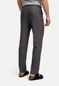 Pantalones gris a rayas con un ajuste entallado, que cuentan con bolsillos traseros y una textura suave, combinados con sandalias negras sin hebillas.