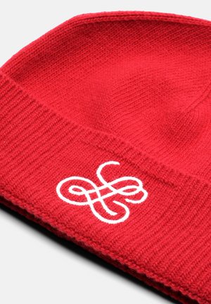 Red knit beanie with ribbed texture. Features a white embroidered design on the front. Soft material, tapered top.