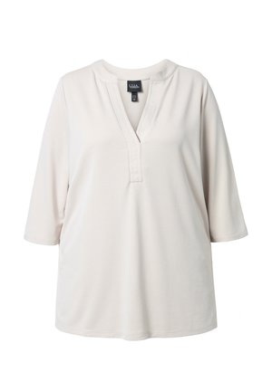 Flødefarvet, langærmet skjorte med rund halsudskæring og et V-formet snit med påsyede lodrette folder.