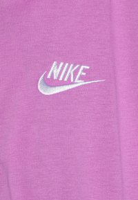 Tecido roxo com um acabamento texturizado, apresentando um logótipo da Nike bordado em branco e o swoosh na parte da frente.