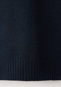 Gros plan sur un tissu tricoté bleu marine foncé avec ourlet côtelé, montrant un matériau en laine doux et texturé.