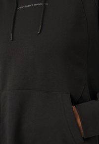 Sweat à capuche noir avec poche avant et cordons, arborant un petit logo blanc "Jordan Sports" près de l'encolure.