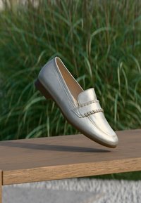 Metallic silver loafers with a smooth leather finish, featuring a stitched design on the upper and a low-profile rubber sole.