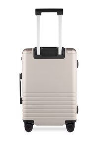 Hartschalenkoffer in hellbeige, mit einem Teleskopgriff, schwarzen Akzenten, strukturierten Oberflächen und vier schwarzen Rollen für Mobilität.