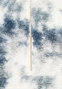 Chaqueta de forro polar peludo y con estampado en tonos blancos y azules, con un zipper central dorado y una superficie suave y texturizada.