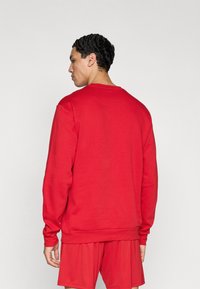 Κόκκινο φούτερ με μακριά μανίκια και ριμπ τελειώματα, με στρογγυλή λαιμόκοψη και άνετη εφαρμογή. Ομαλή υφή, απλό σχέδιο, χωρίς σχέδια ή μοτίβα.