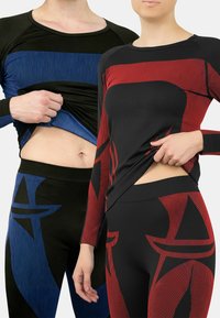 Black and red activewear featuring ribbed texture and abstract designs, paired with black and blue striped leggings. Tight-fitting style.