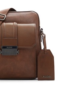 Borsa a tracolla in pelle sintetica marrone con tasca frontale, finitura testurizzata, hardware argentato e etichetta rimovibile con logo "ALDO".