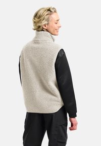 Gilet in fleece beige chiaro con tessuto testurizzato, colletto alto e maniche nere. Presenta un orlo regolabile e tasche laterali.