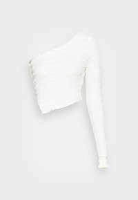 Vit top med en axel och en texturerad, ribbad design. Har en kortad längd och lång, åtsittande ärm med fransade kanter.