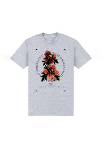 Camiseta gris de manga corta con un gráfico floral en rojo y verde, con elementos de texto dispuestos en un diseño circular alrededor de las flores.