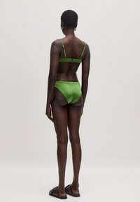 Groene satijnen bikini-set met dunne bandjes en een haaksluiting, met een minimalistisch ontwerp en een zachte textuur in een hoge snit.