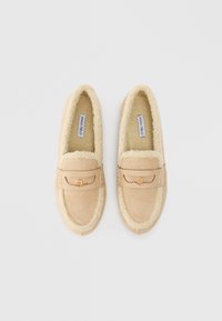 Μπεζ σουέτ παντόφλες με αφράτη εσωτερική επένδυση, ραμμένη περίμετρο και διακοσμητική ταινία με χρυσό κουμπί.