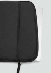 Čierny polstrovaný obal na laptop s hladkým povrchom, vrchným zipsom a štíhlym profilom, ktorý je čiastočne otvorený, aby odhalil strieborný laptop vo vnútri.