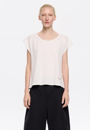 T-shirt a maniche corte, di colore bianco sporco, realizzato in tessuto leggero. Collo tondo, vestibilità morbida, con ricamo rosso discreto sull'orlo inferiore.