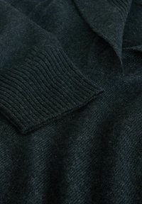 Dark wool sweater with ribbed cuffs, v-neck design, and a textured surface. The material appears soft and warm, suitable for colder weather.