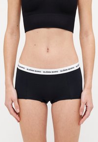 Boxer shorts neri in cotone, con un elastico bianco in vita riportante il logo "BJÖRN BORG". Tessuto morbido e taglio aderente.