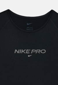 Melnā Nike Pro Dri-FIT sporta krekls ar apaļu kaklu, ar baltu drukātu tekstu un logo, izgatavots no mitrumu atturoša materiāla.